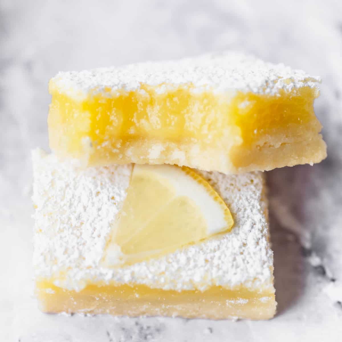 A lemon bar up close with a bite taken out of it.