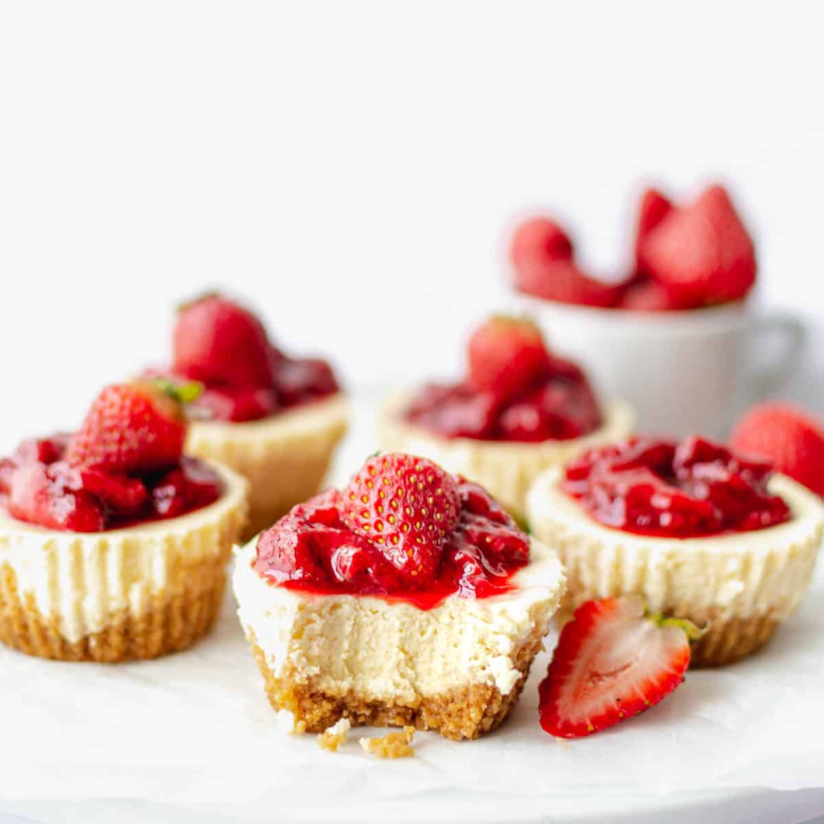 A mini strawberry cheesecake with a bite taken from it.
