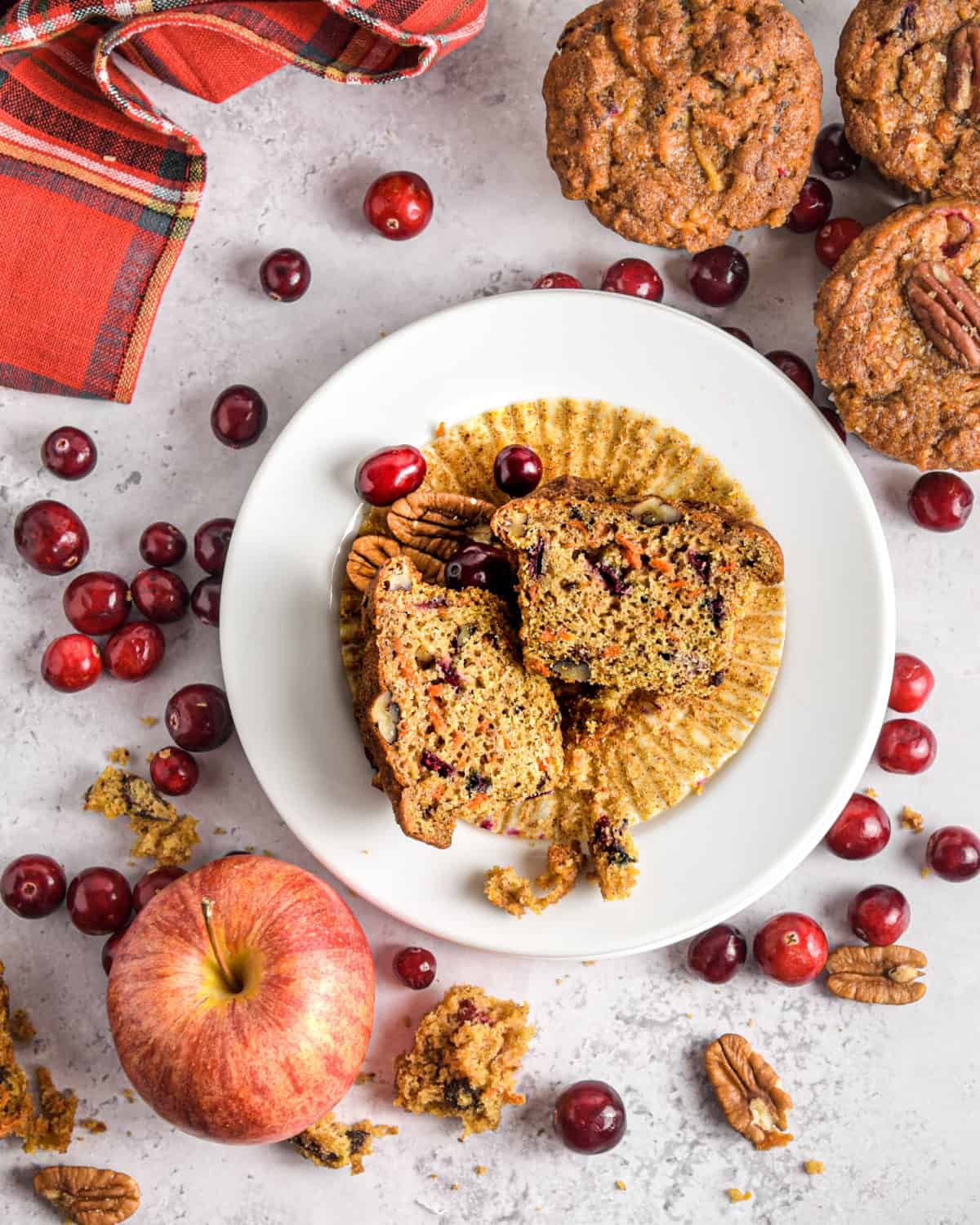 An overhead shot of apple muffins surrounded by fresh cranberries and apples.