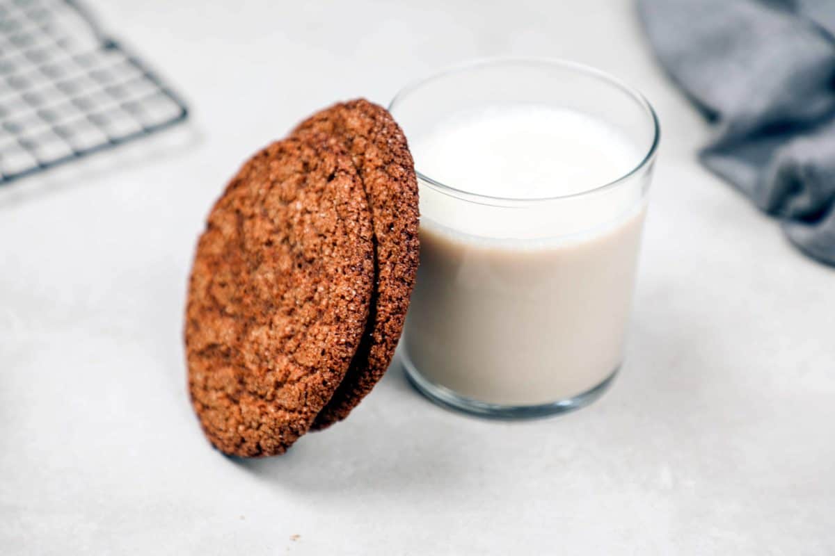 Two old fashioned molasses cookies with a glass of milk.