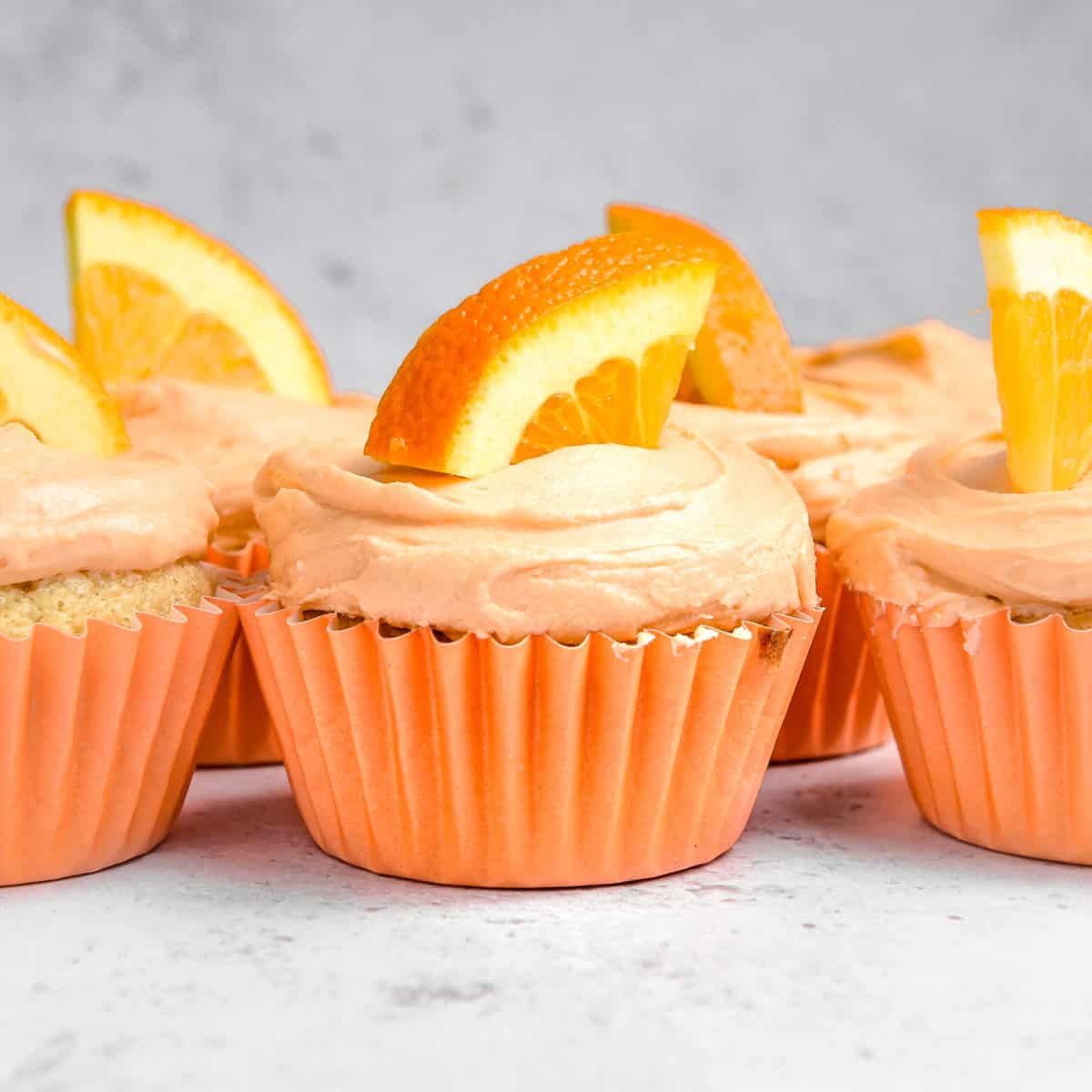 Orange cupcakes with a slice of orange on top.