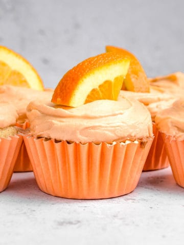Orange cupcakes with a slice of orange on top.