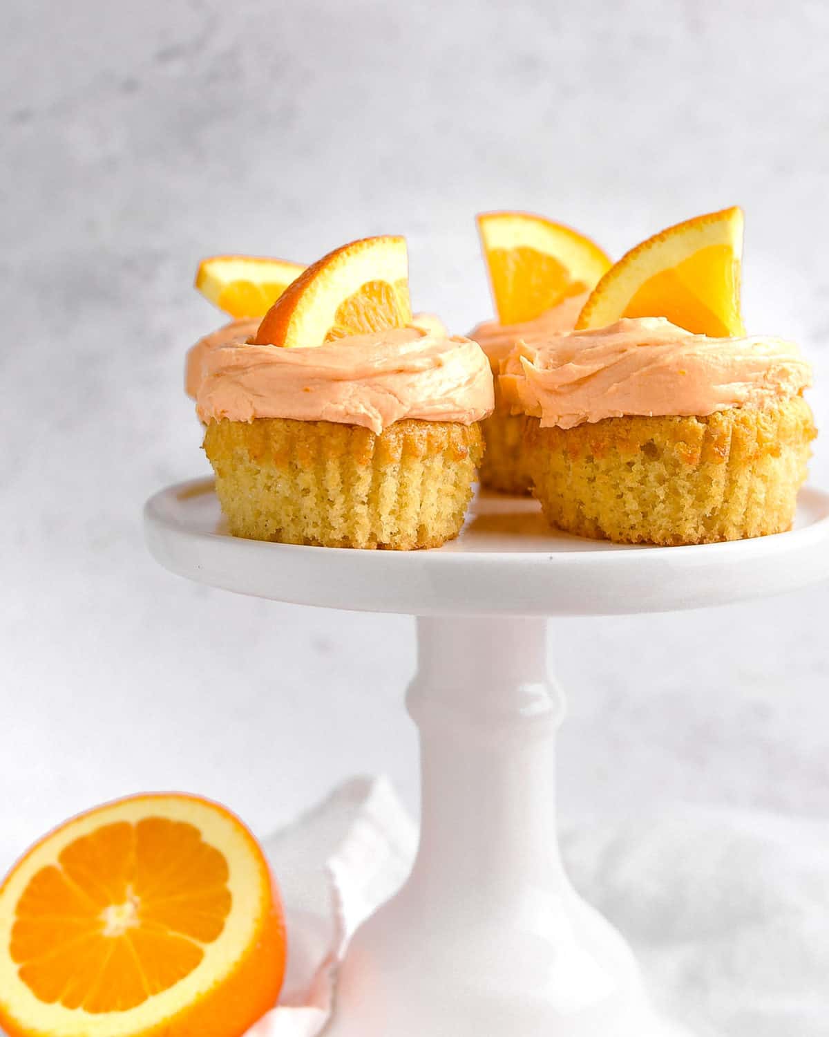 Cupcakes on a stand topped with orange wedges.