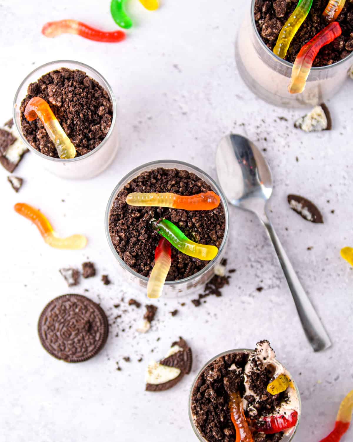 An overhead shot of gummy worms in dirt cup desserts.
