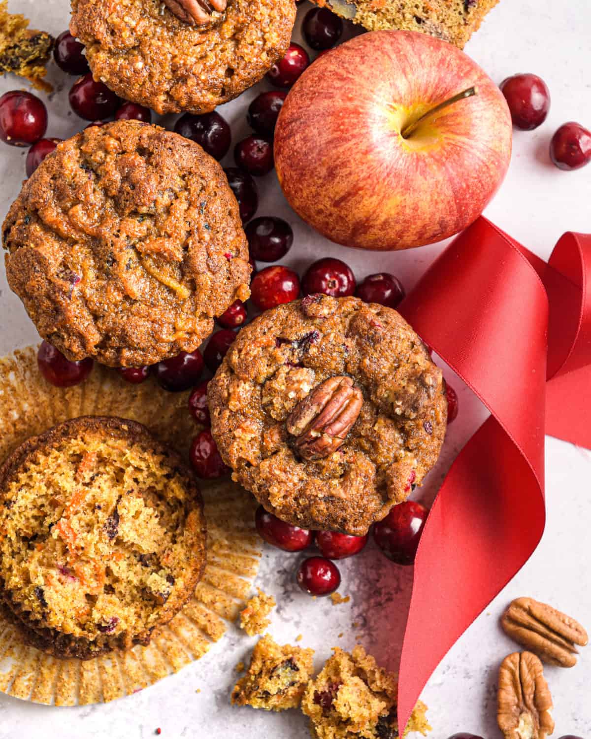 An overhead shot of several muffins with a festive ribbon and apple.