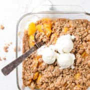 An overhead shot of peach crisp topped with ice cream.