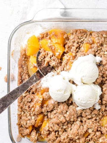 An overhead shot of peach crisp topped with ice cream.