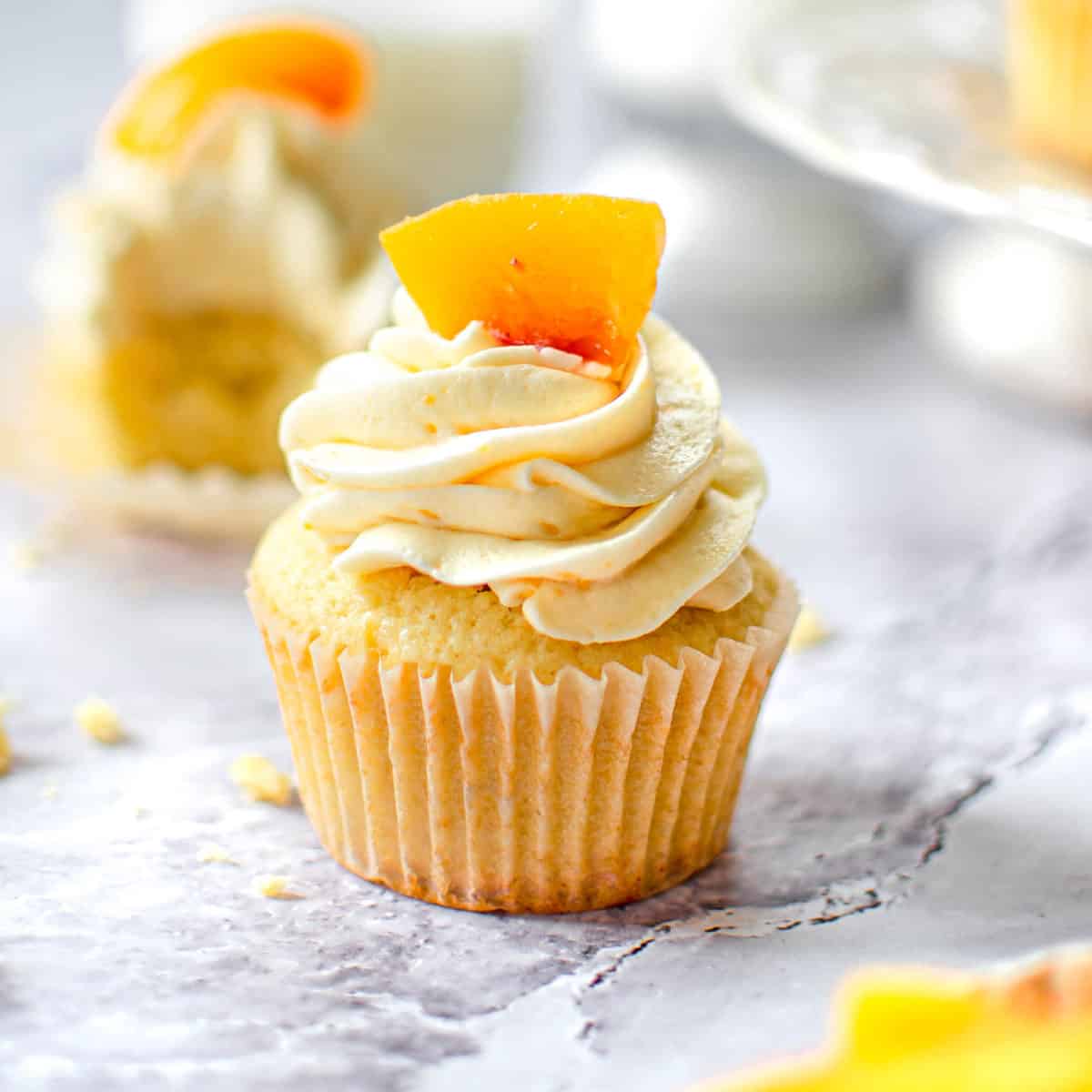 Close up of cupcake topped with a fresh peach.