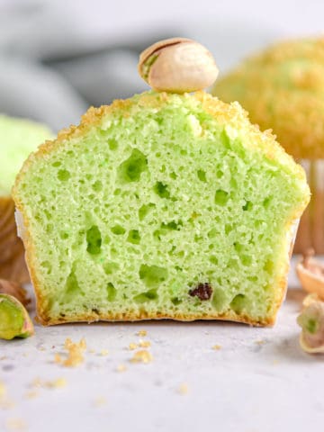 A pistachio muffin sliced in half looking at the inside.