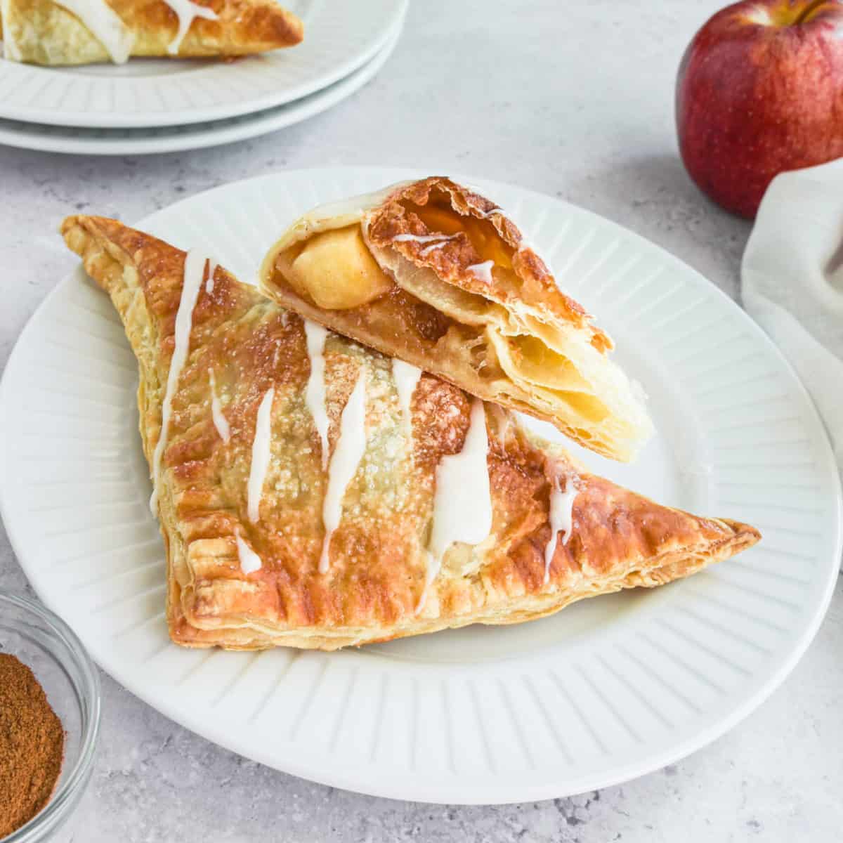 Puff pastry apple turnovers on a white plate.