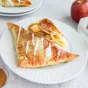 Puff pastry apple turnovers on a white plate.