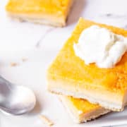 Pumpkin pie bars close up on a plate topped with whipped cream.