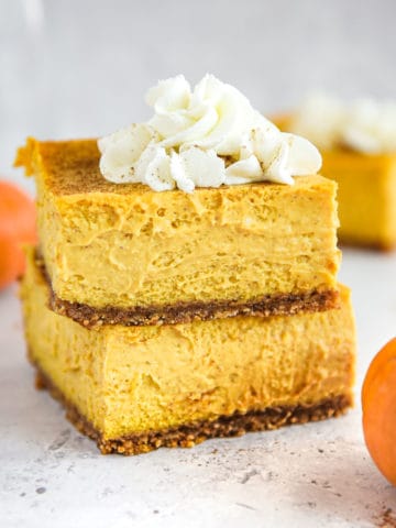 Two pumpkin pie cheesecake bars on top of each other.