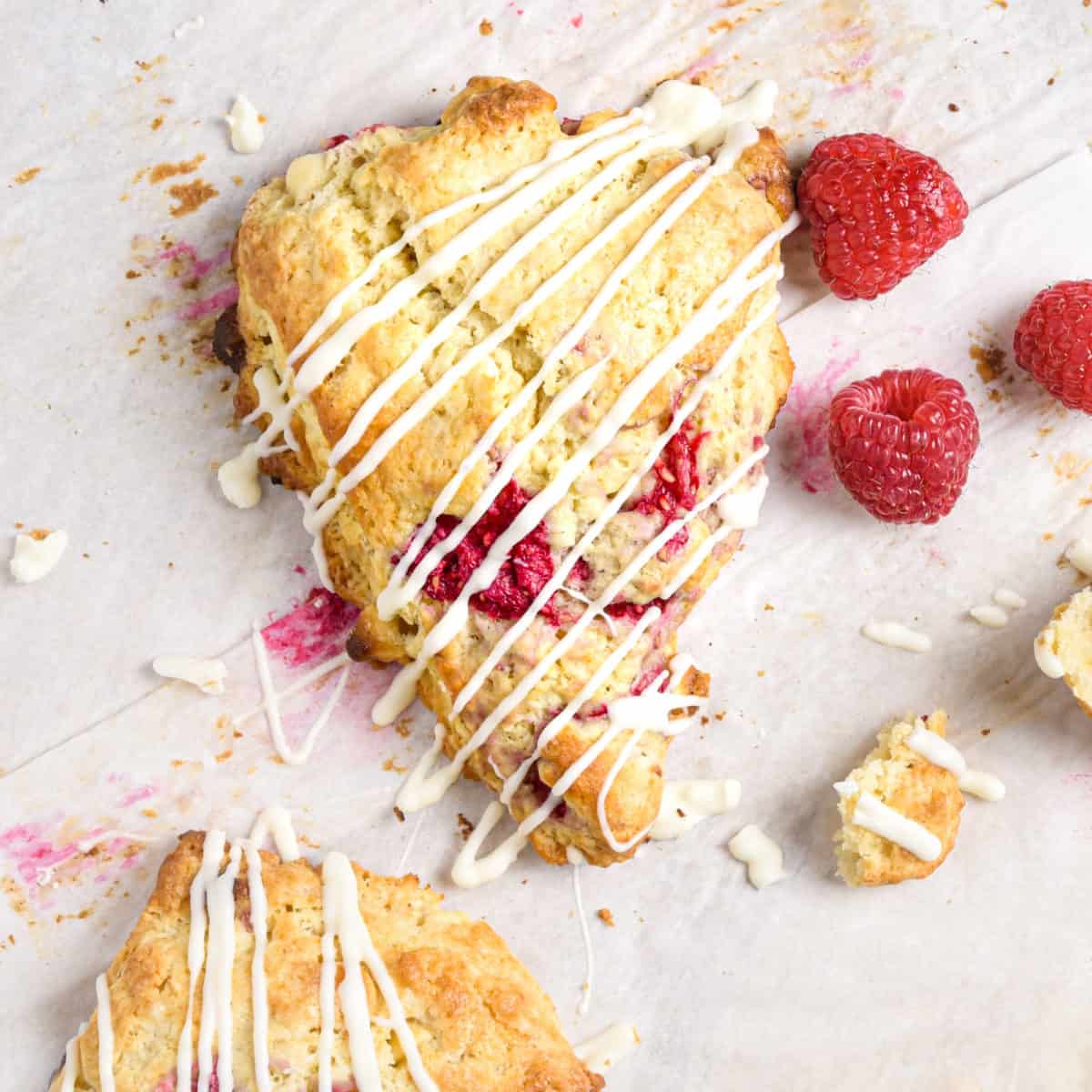 A scone with white chocolate drizzled on top of it.