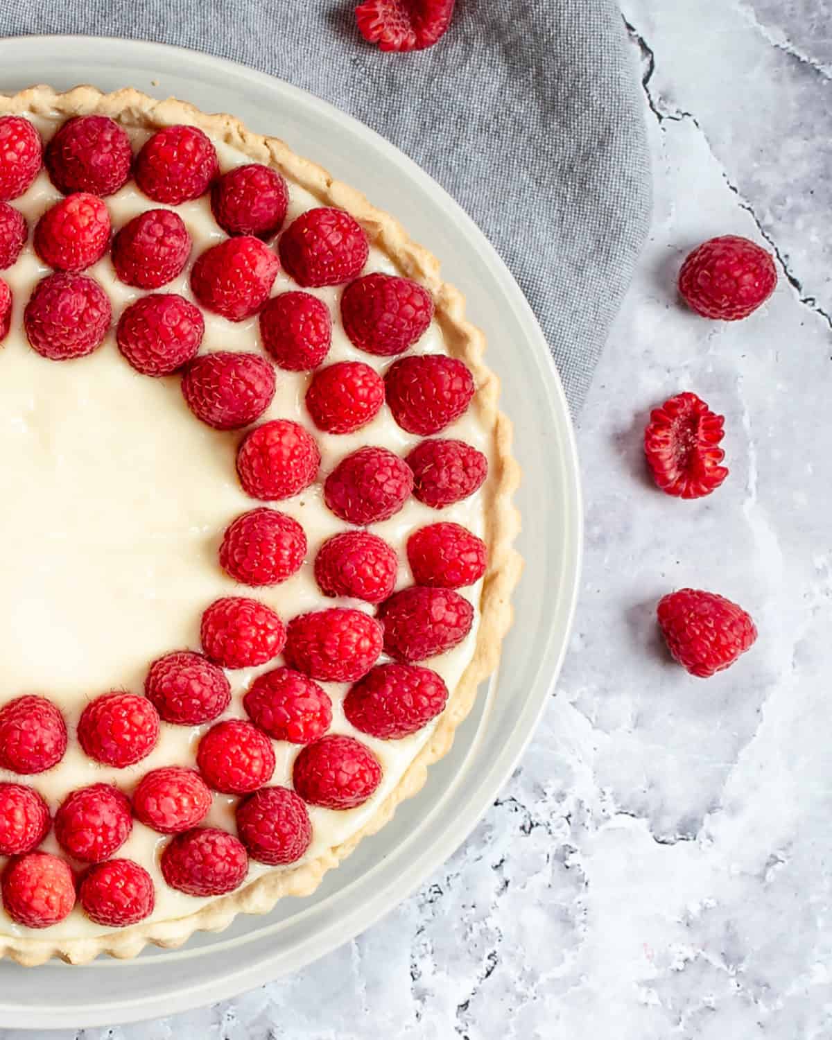 A close up of custard tart topped with raspberries.