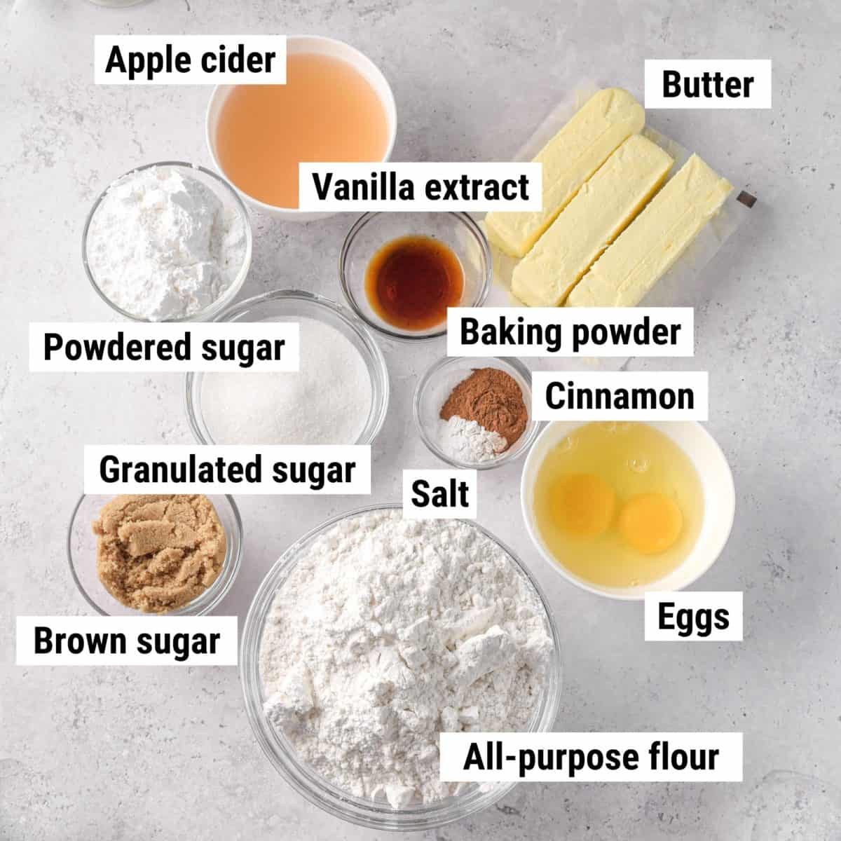 The recipe ingredients used to make apple cider cupcakes spread out on a table.