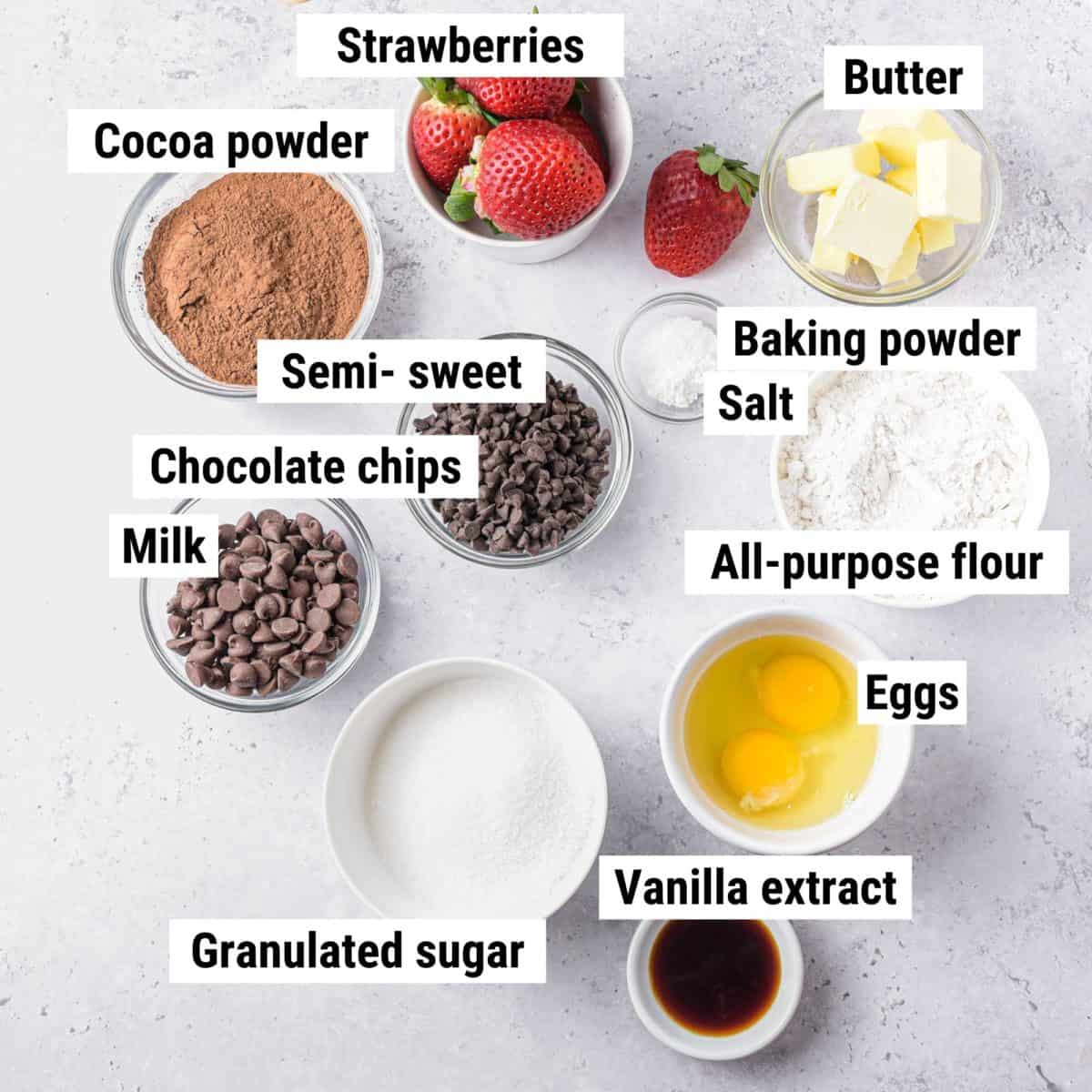 The ingredients used to make brownies with strawberries laid out on a table.