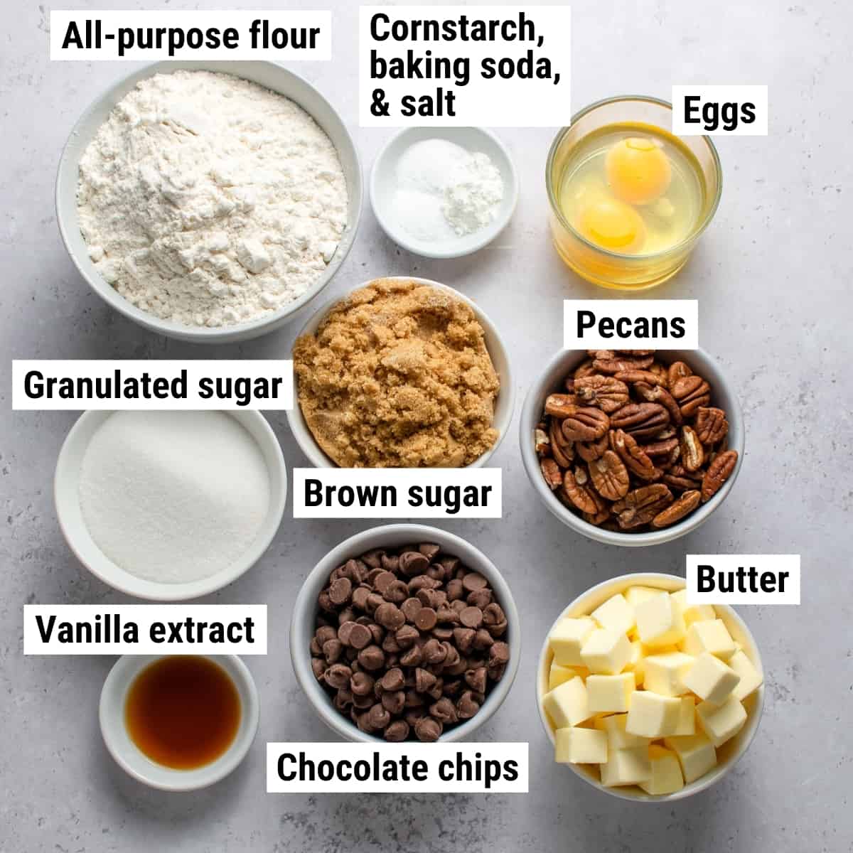 The ingredients used to make chocolate chip pecan cookies spread out on a table.