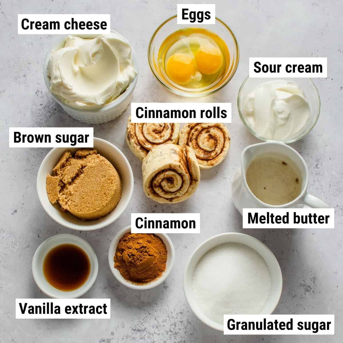 The ingredients used to make cinnamon roll cheesecake spread out on a table.