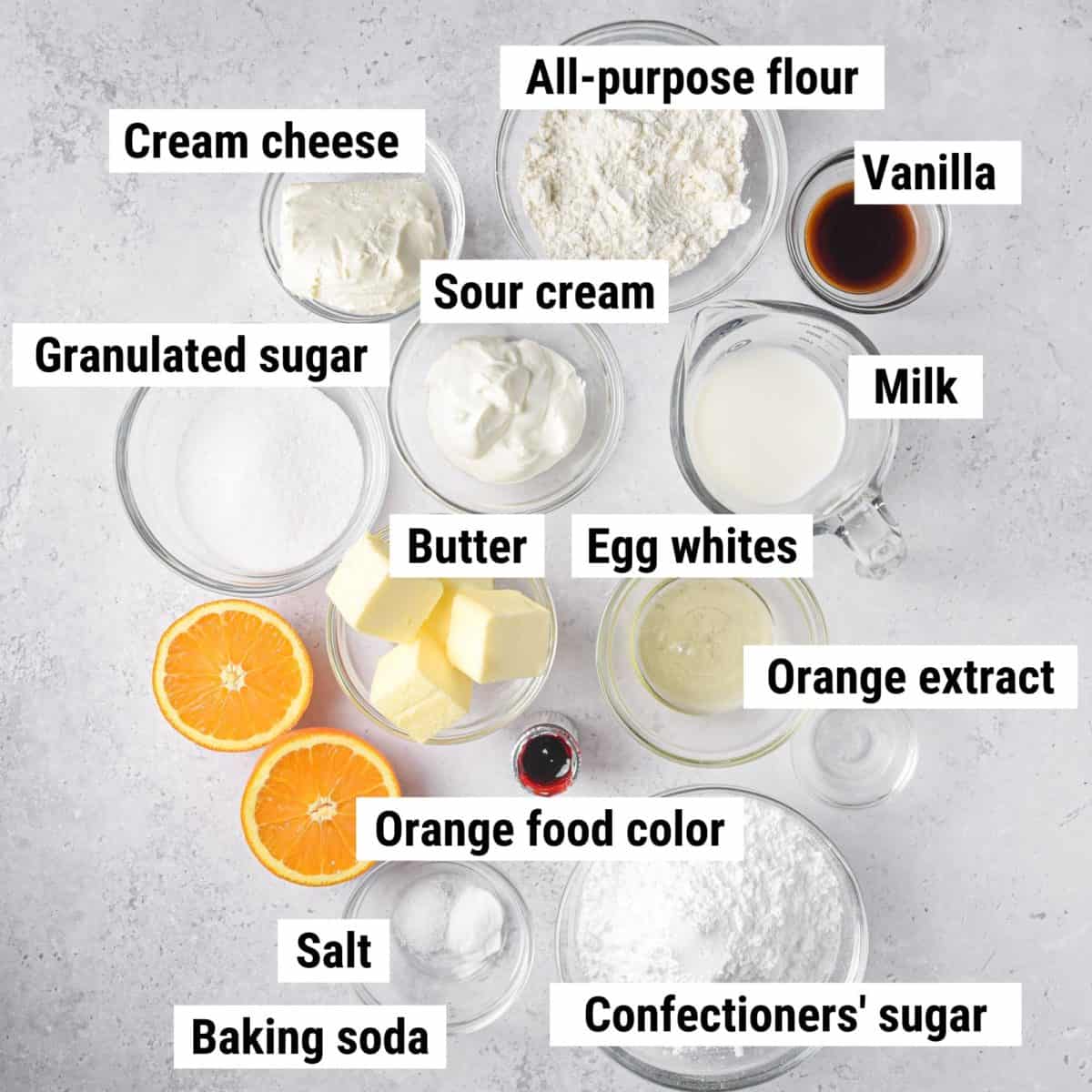 The ingredients used to make orange cupcakes spread out on a table.