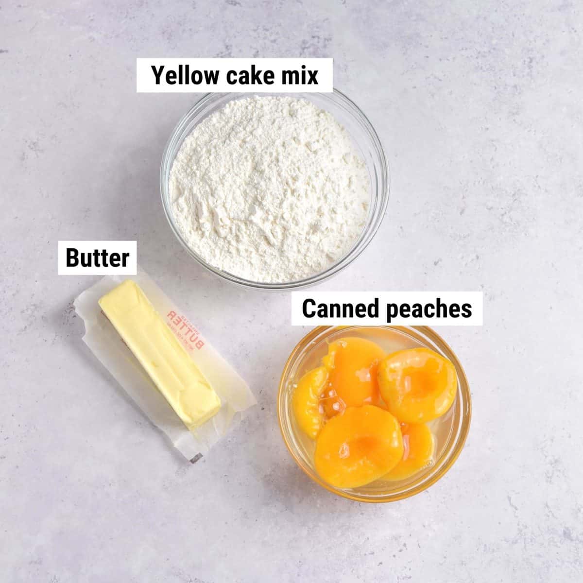 The ingredients used to make peach cobbler with cake mix laid out on a table.
