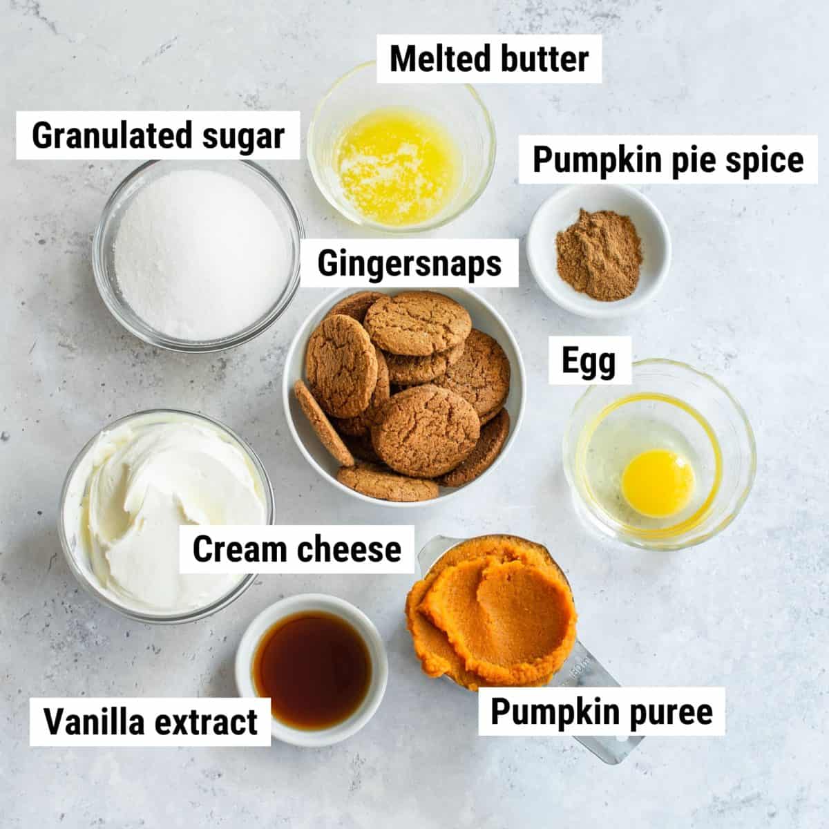 The ingredients used to make pumpkin mini cheesecakes spread out on a table.