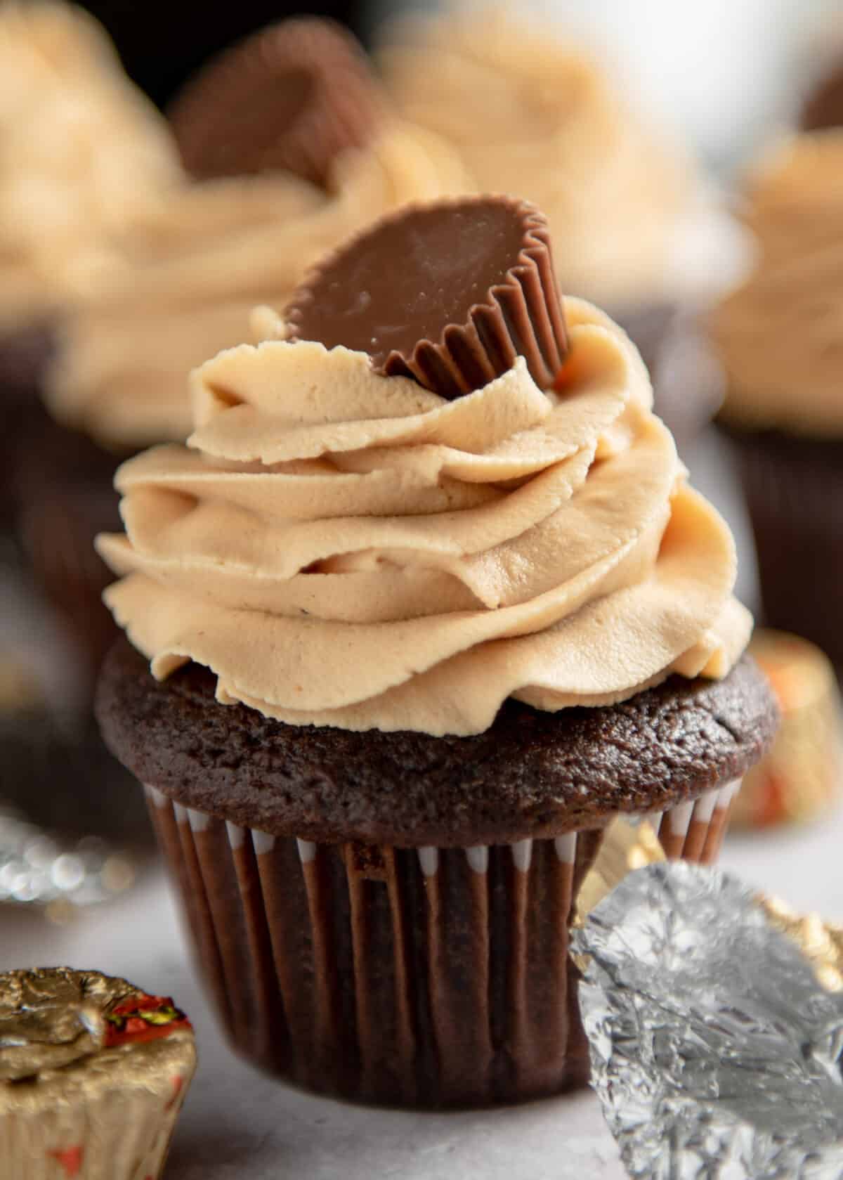 A mini Reese's treat on top of the frosting on a chocolate cupcake.