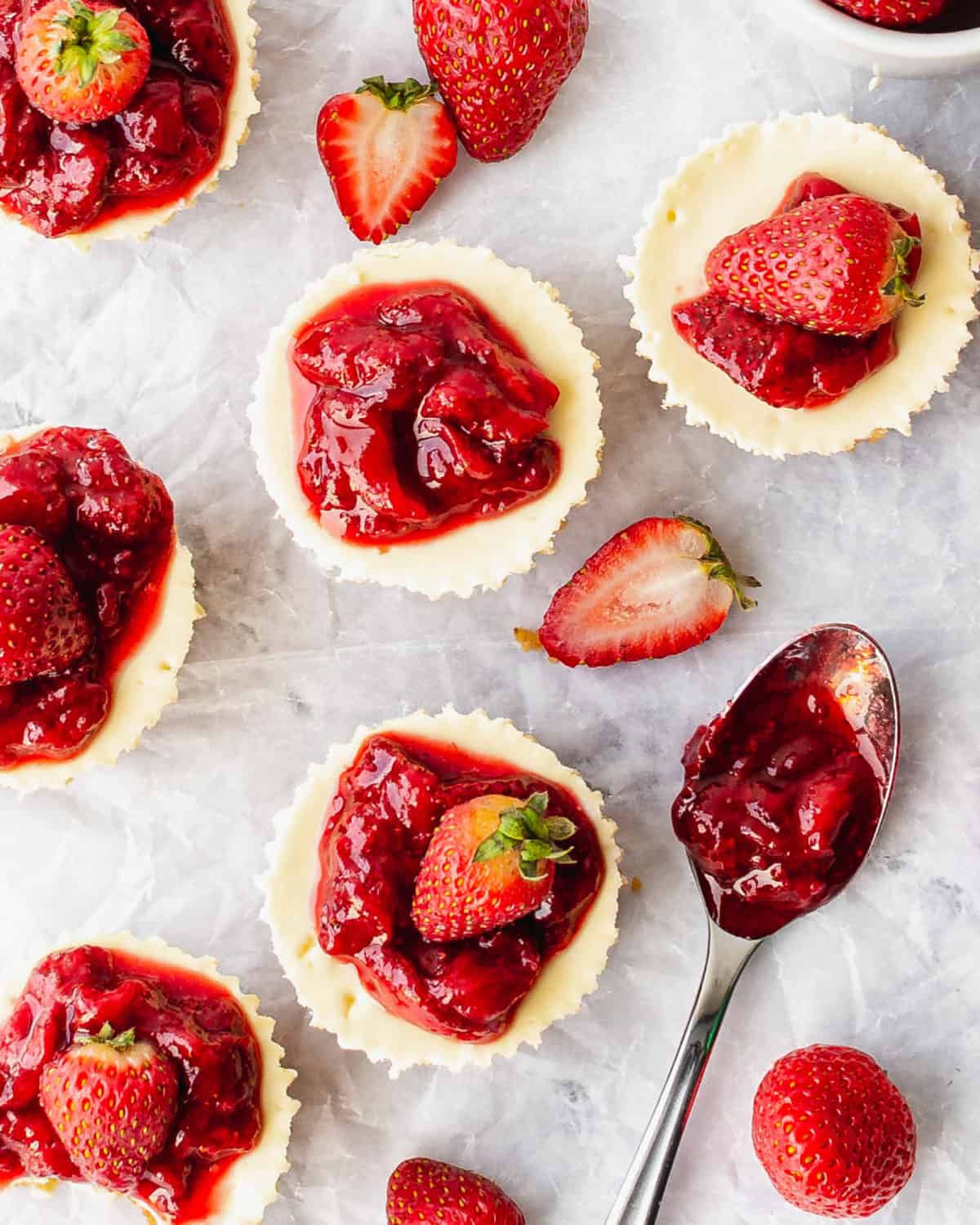 Several mini strawberry cheesecakes on a table.