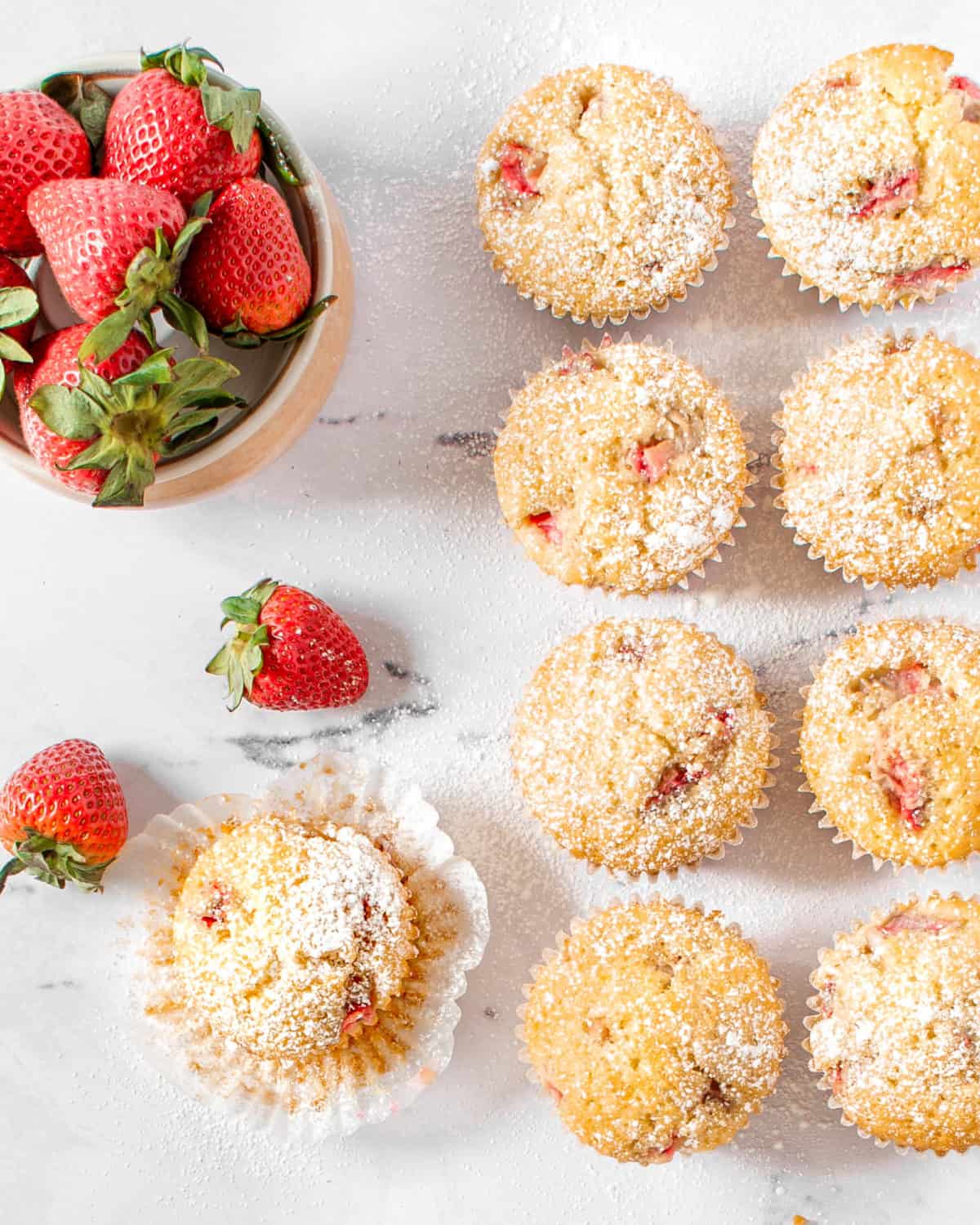 Several strawberry lemon muffins spread out on a table.