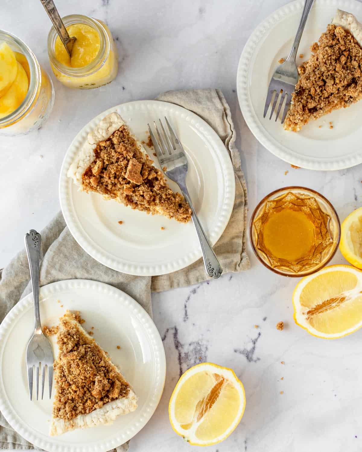 Three slices of lemon crunch pie on plates with forks on a table.