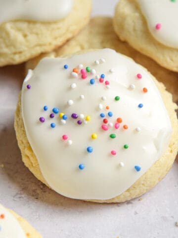 A sour cream cookie up close with colored sprinkles on it.
