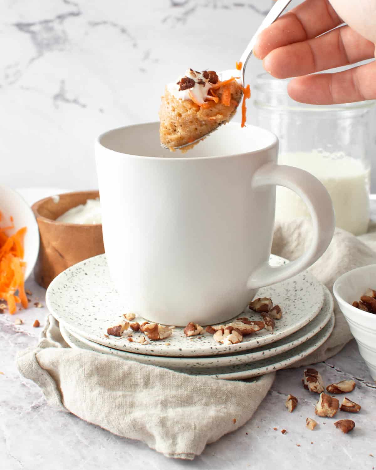 A spoonful of carrot mug cake with almonds.