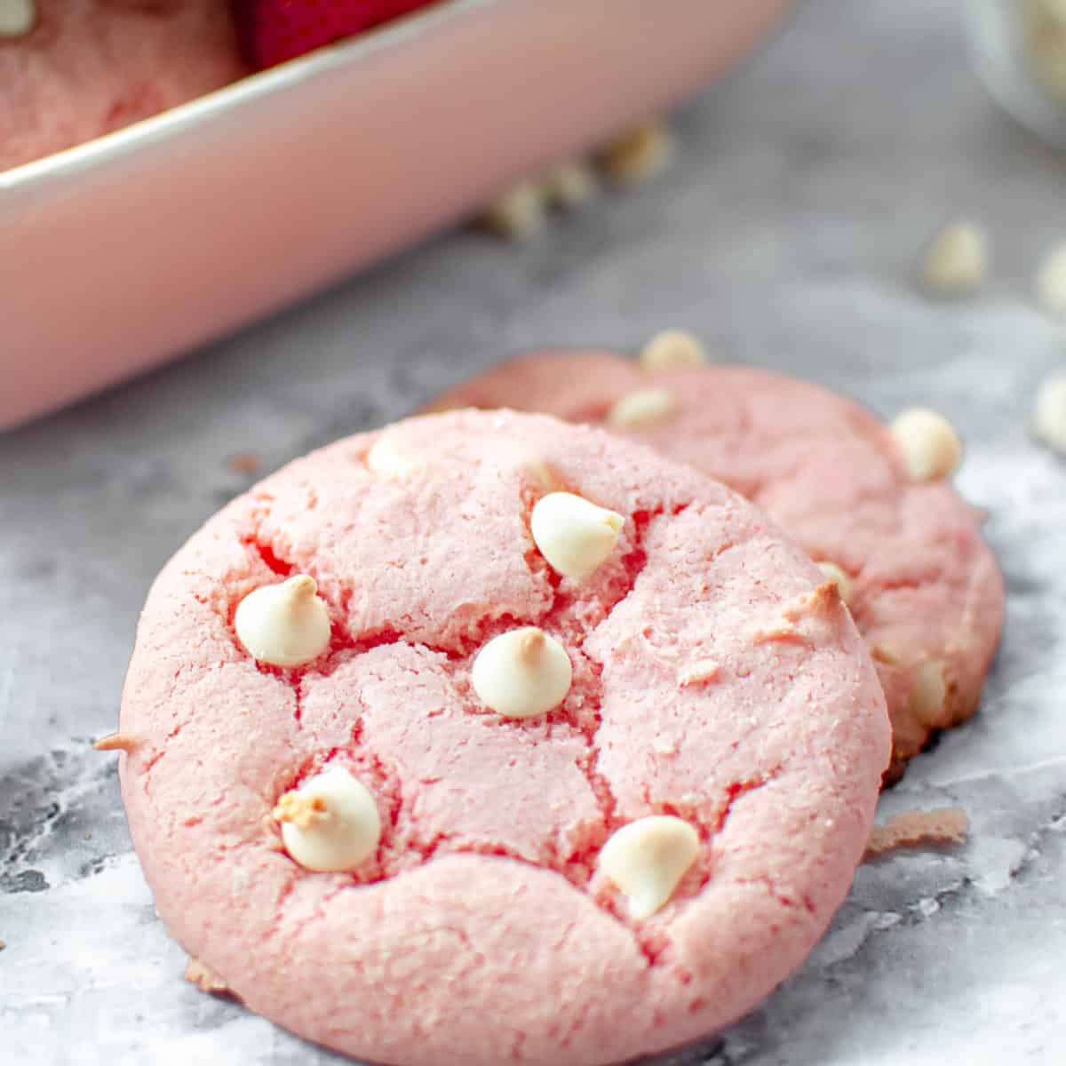A close up of a strawberry cake cookie with white chocolate chips.