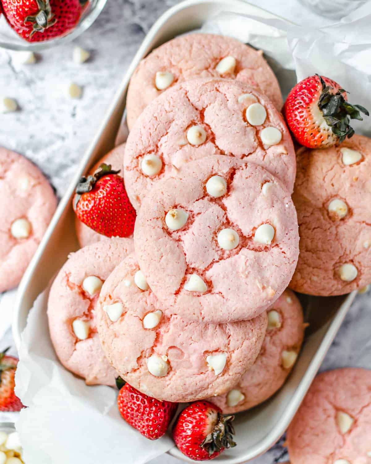 Overhead shot of strawberry cake cookies in a dish with fresh strawberries.