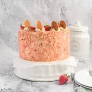 A strawberry crunch cake on a stand.