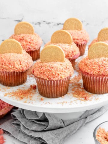 Several strawberry crunch cupcakes on a stand.