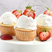 Three strawberry filled cupcakes displayed on a cake stand.