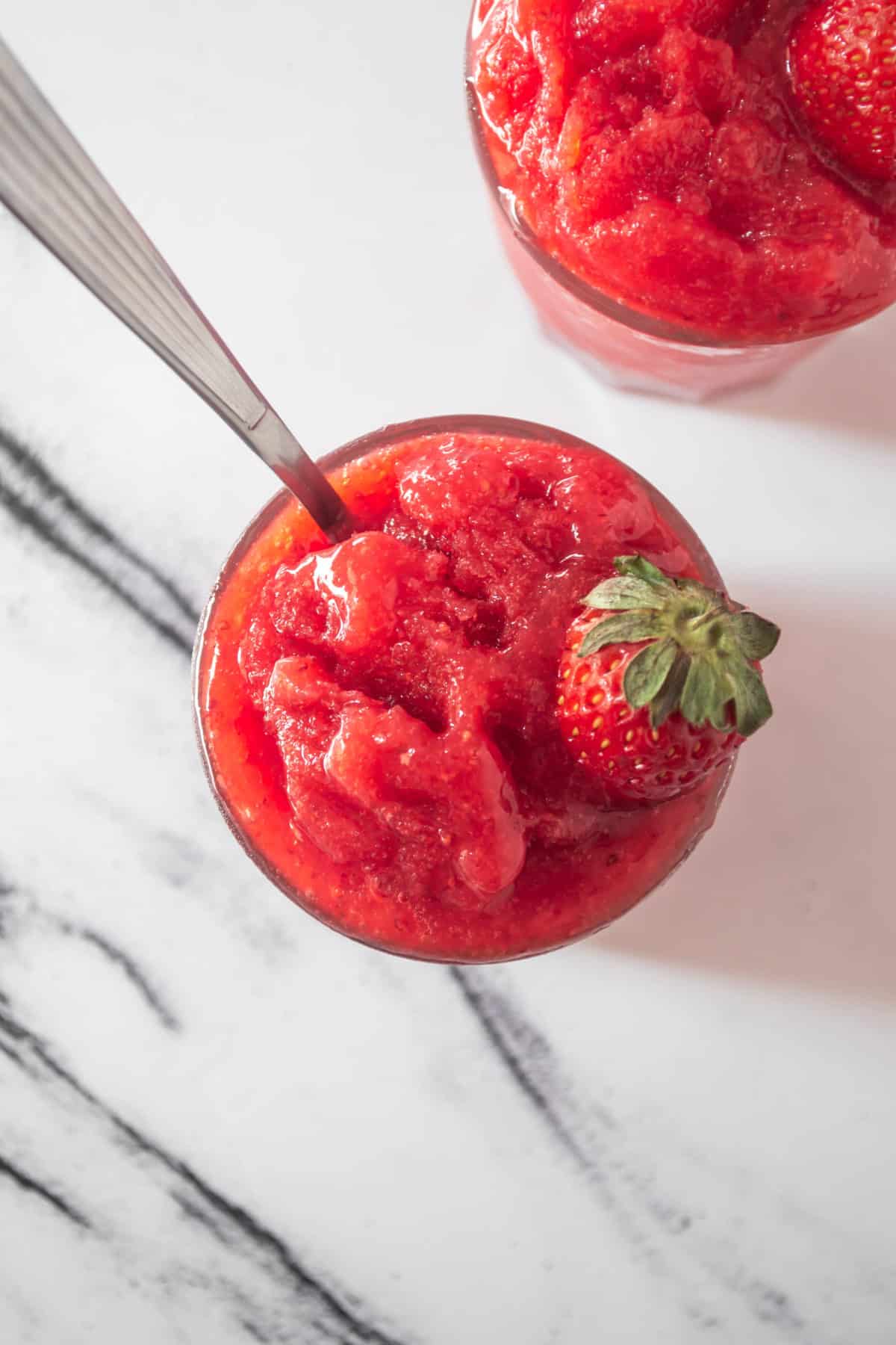 A close up of strawberry granita topped with a strawberry.