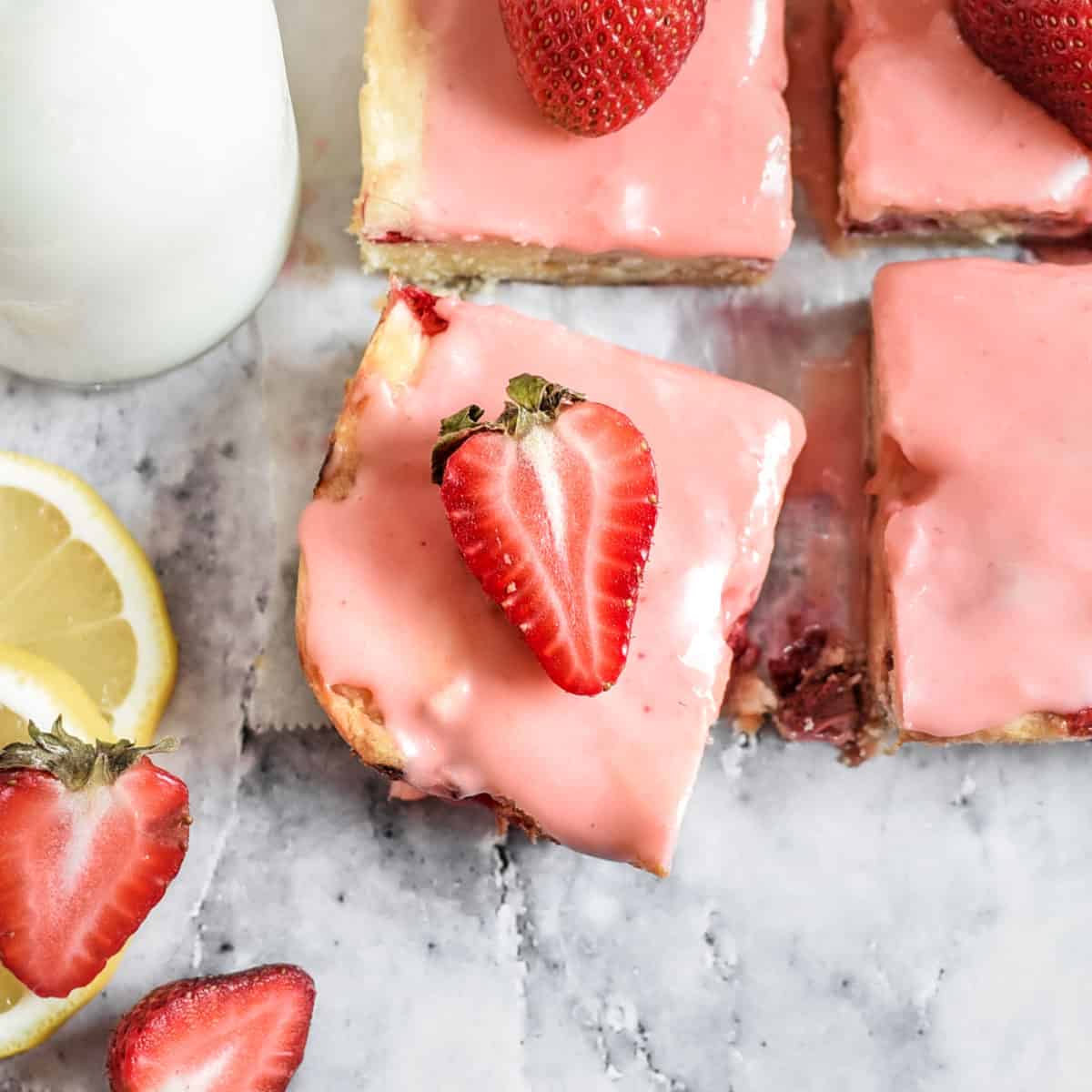 A strawberry lemon blondie up close with a fresh strawberry halve on top of it.