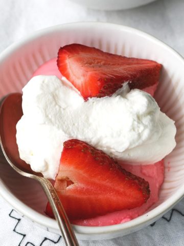 A bowl of homemade strawberry pudding topped with whipped cream.