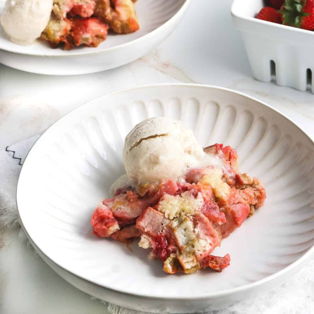 A bowl with strawberry cobbler topped with vanilla ice cream.
