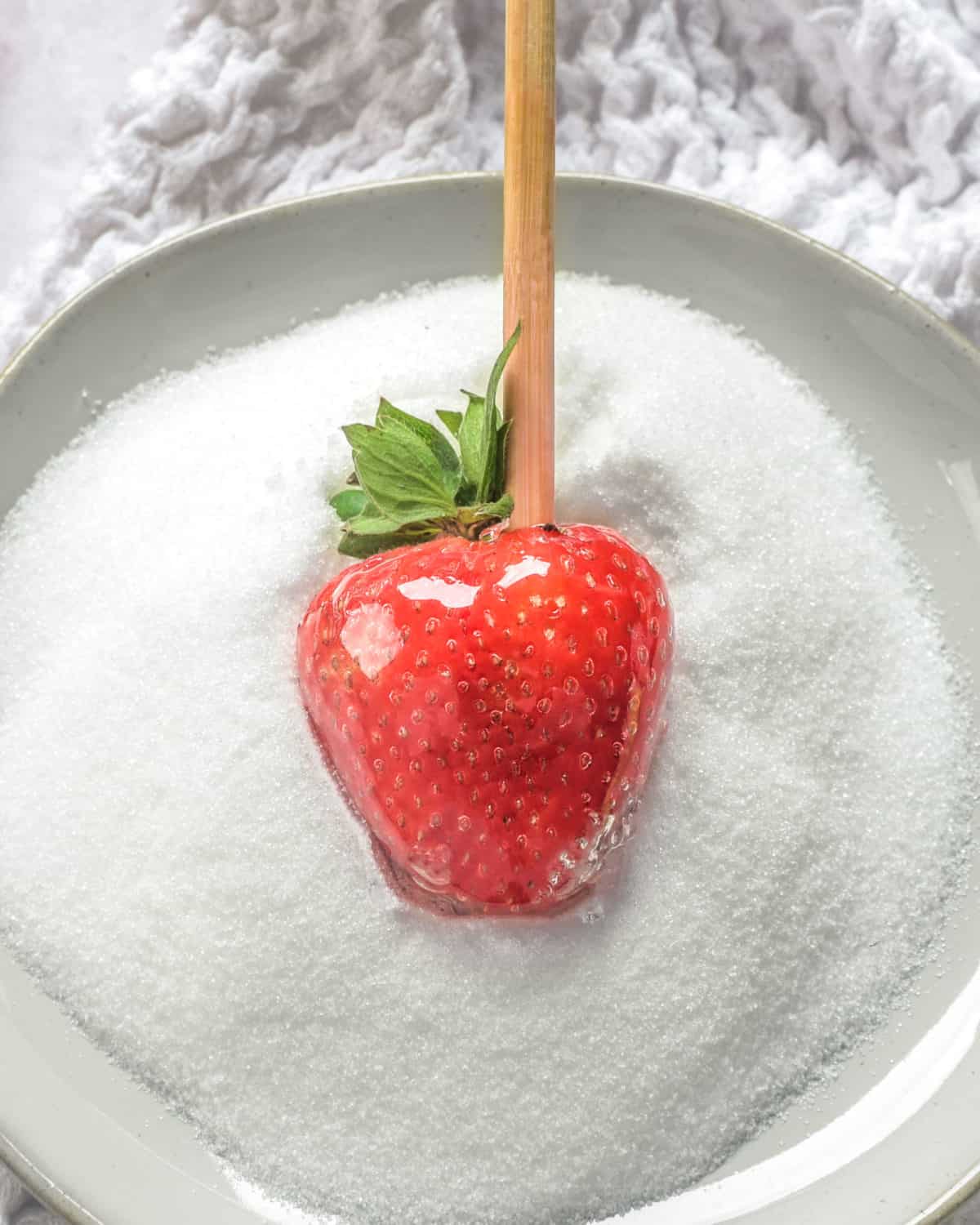 A candy strawberry in a bowl of sugar.
