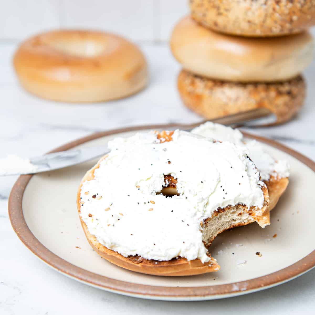 Bagel on plate with cream cheese spread.