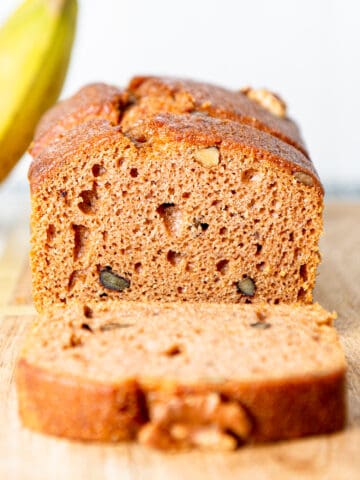 Sliced banana bread loaf, with a banana in the background.