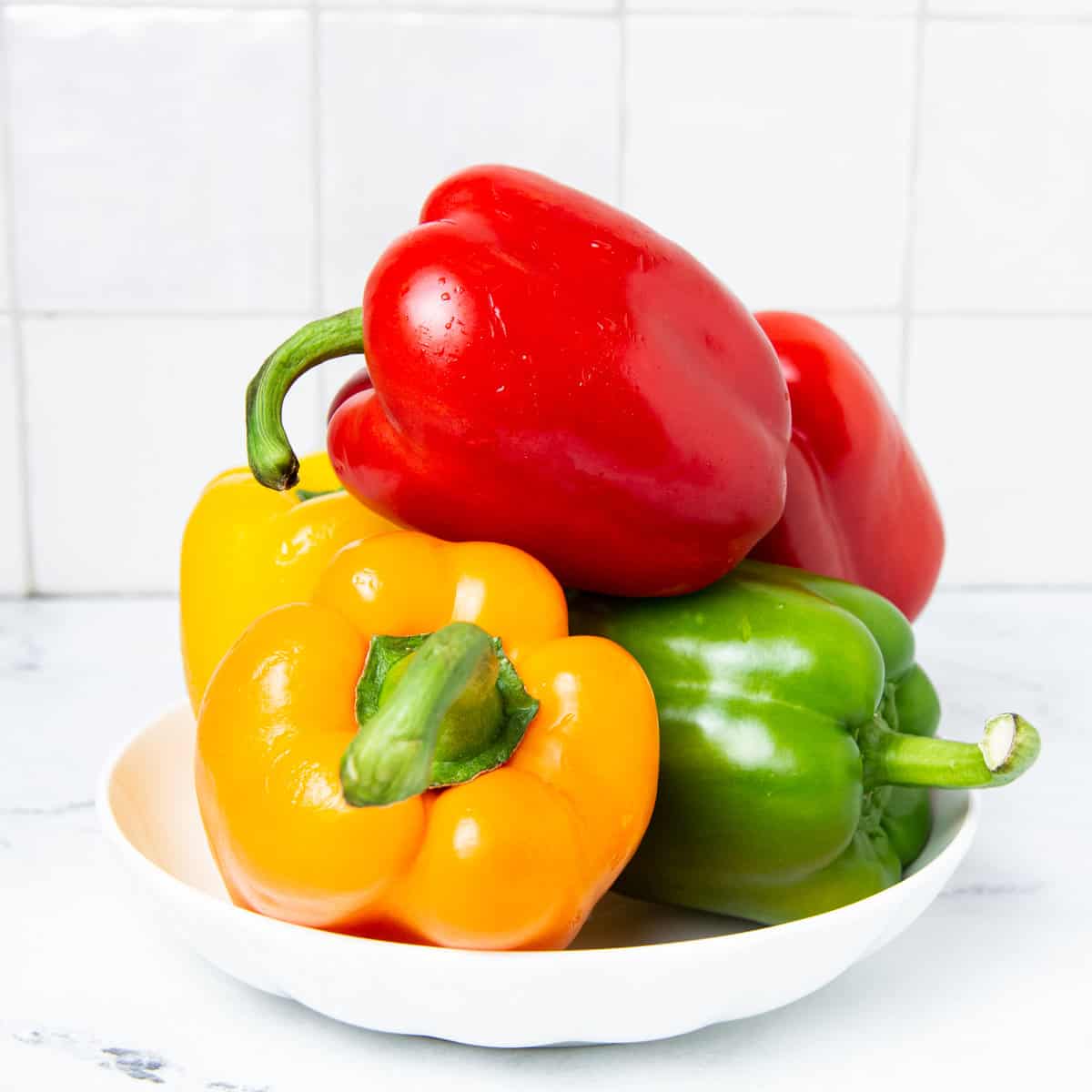 Bell peppers in a white plate on a kitchen counter.
