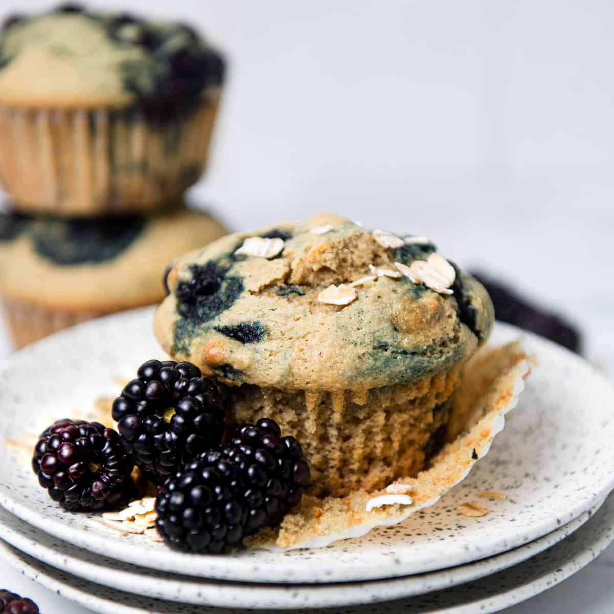 Blackberry muffin on a plate with decorative blackberries.