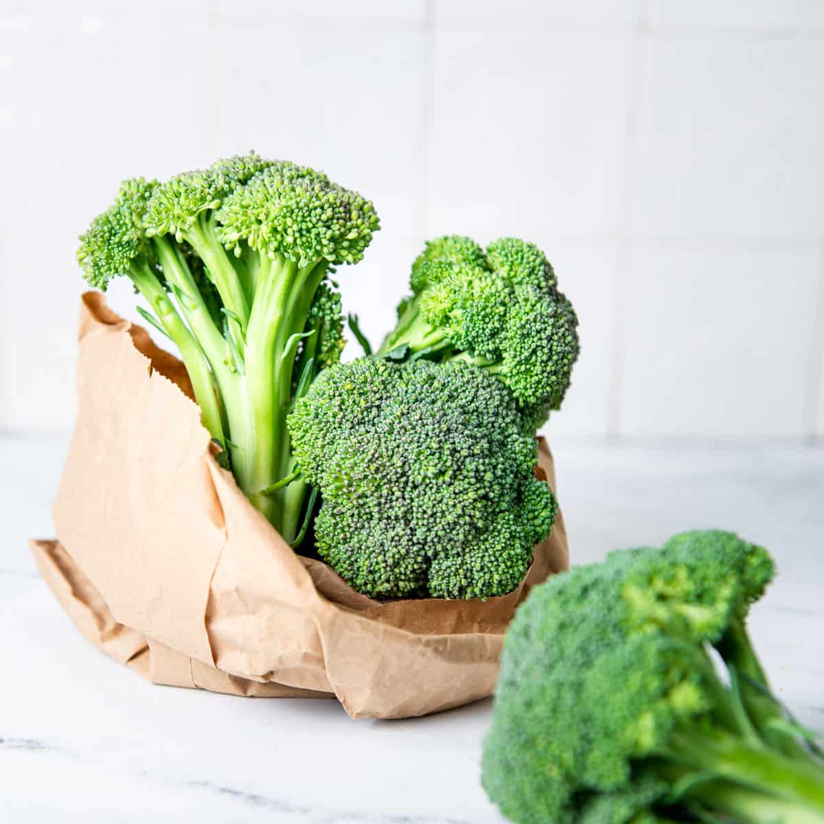 Broccoli in a paper bag on a counter.
