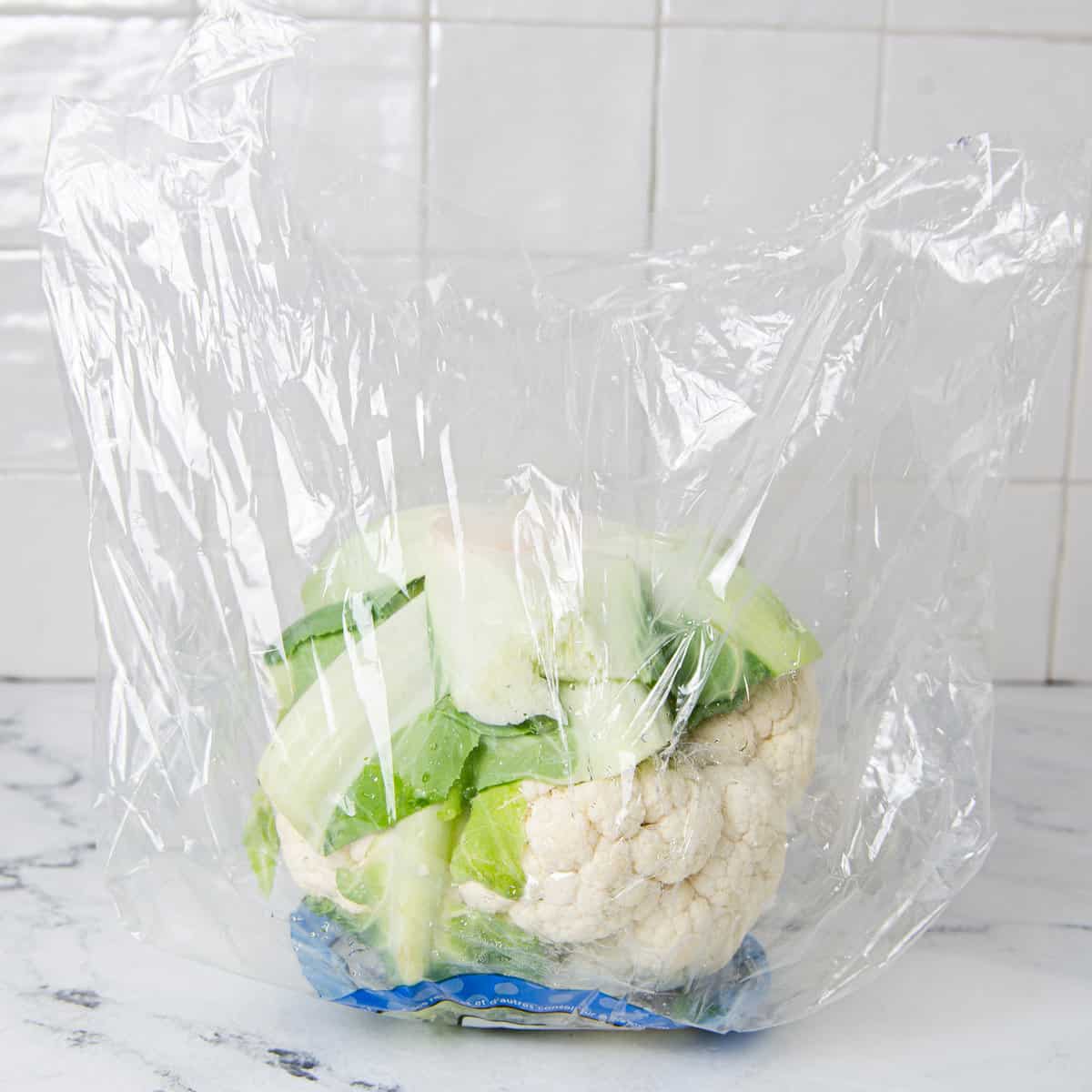 Cauliflower in a loose bag on a kitchen counter.