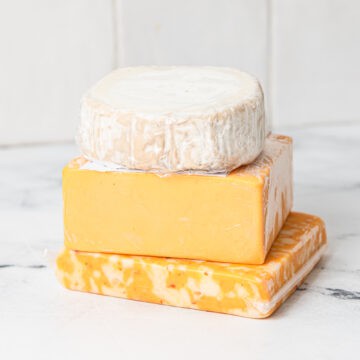3 cheese types stacked on top of each other on a kitchen counter.