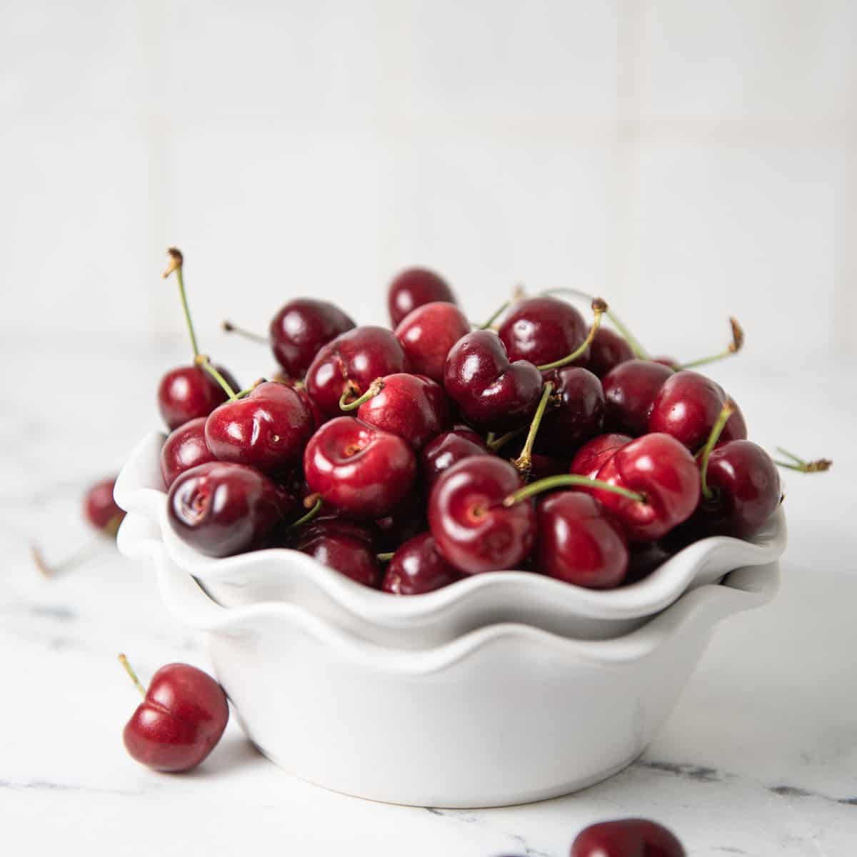 Cherries in a bowl on a counter.